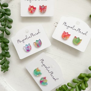 May include: Three pairs of colorful, abstract tulip-shaped earrings on white cards with the text "Magnolia Marsh" printed on each card.