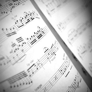 May include: Black and white sheet music with musical notes and markings. The text "marcato" is visible on the sheet music.