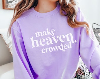 May include: A lavender sweatshirt with the text "make heaven crowded" in white lettering.