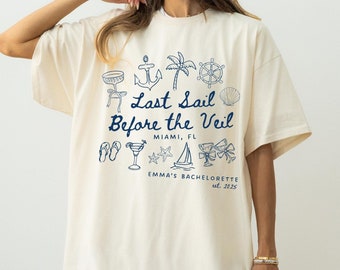 May include: Ivory oversized t-shirt with a navy blue graphic design featuring nautical icons and the text "Last Sail Before the Veil, Miami, FL, Emma's Bachelorette est. 2025".