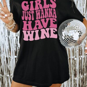Peut inclure: T-shirt noir surdimensionn&eacute; avec un motif rose qui dit "Girls Just Wanna Have Wine".