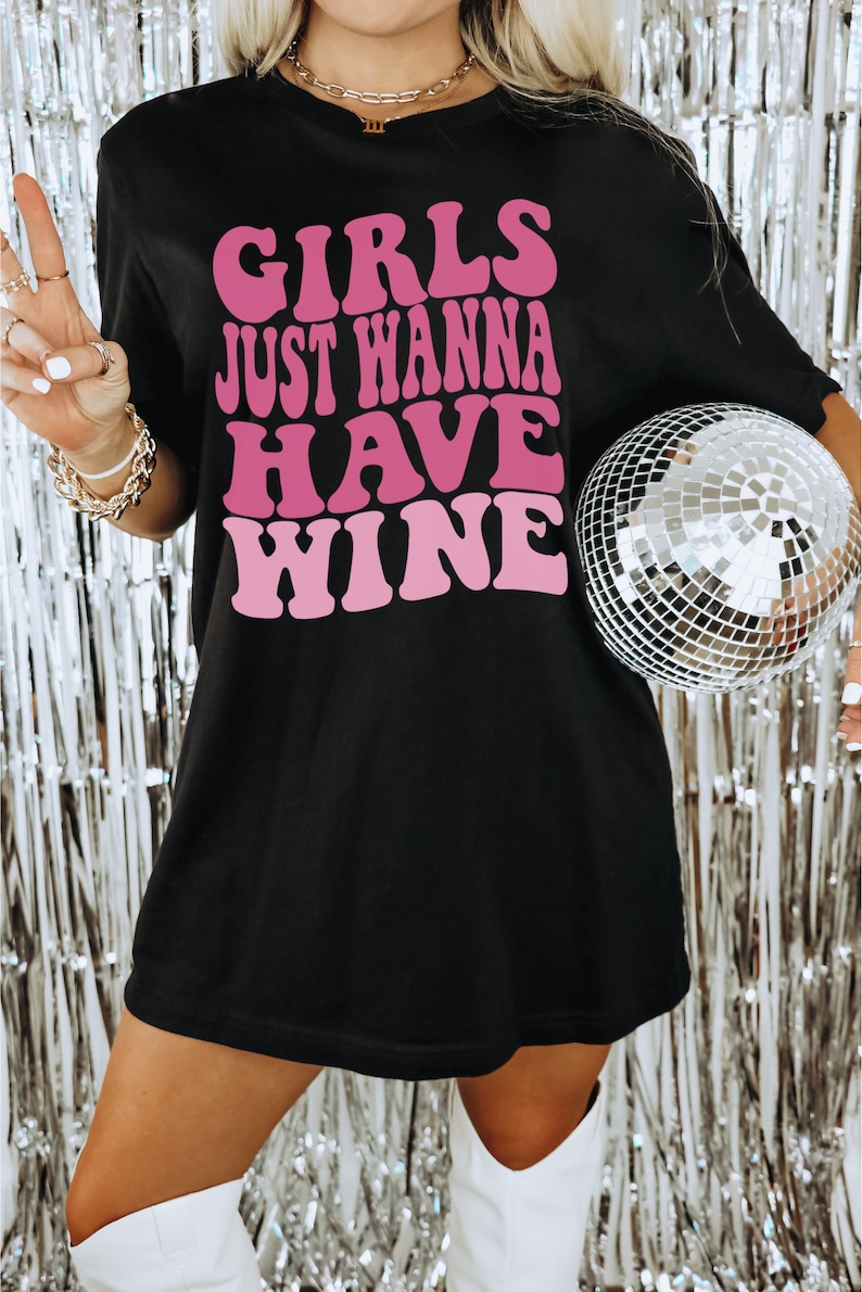 Peut inclure: T-shirt noir surdimensionn&eacute; avec un motif rose qui dit "Girls Just Wanna Have Wine".