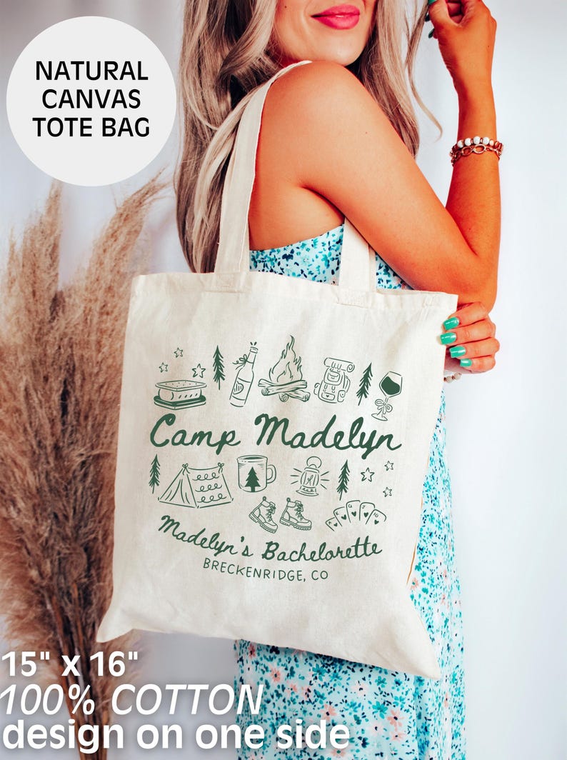 May include: Natural canvas tote bag, 15" x 16", with a green design on one side. The design includes camping-themed illustrations and the text "Camp Madelyn" and "Madelyn's Bachelorette, Breckenridge, CO". Made of 100% cotton.