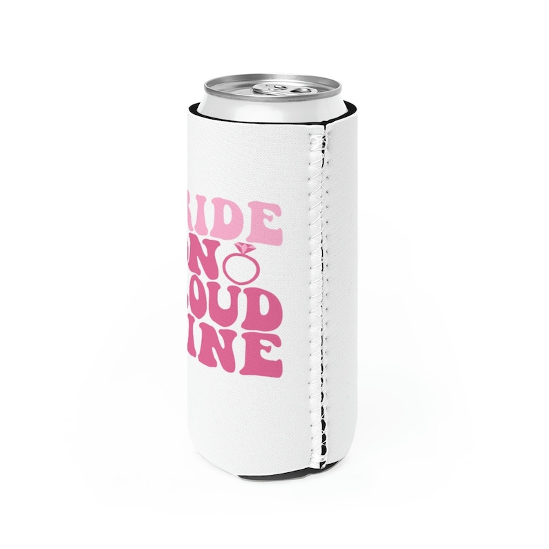 May include: White can cooler with a pink design that says "Bride to be No Doubt Fine" with a pink diamond ring graphic.