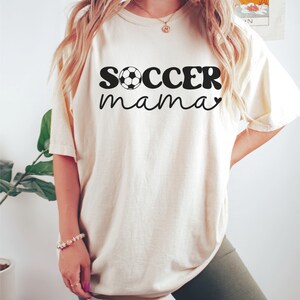 May include: A white t-shirt with the text "soccer mama" in black with a soccer ball graphic.