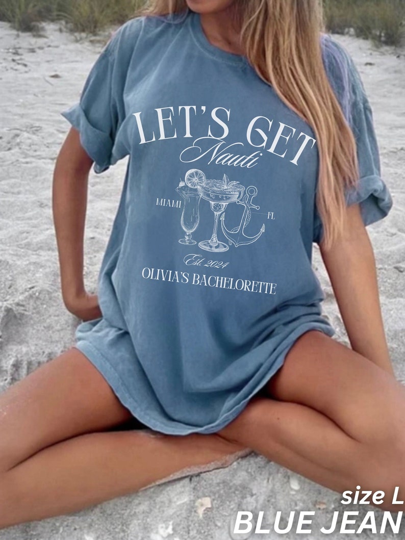 May include: Blue jean-coloured t-shirt with the text "LET'S GET Nauti" in white script. Below the text are illustrations of cocktails, an anchor, and the words "Miami FL" and "Olivia's Bachelorette Est. 2024". The shirt is size L.