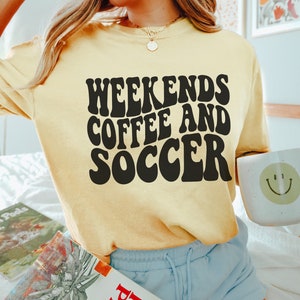 May include: A yellow t-shirt with the text "Weekends Coffee and Soccer" in black retro font.