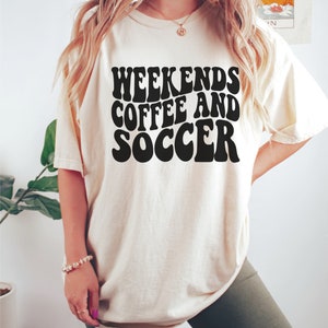 May include: A white t-shirt with the text "Weekends Coffee and Soccer" in black retro-style lettering.