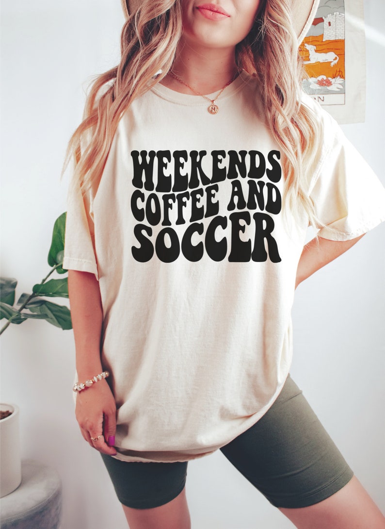 May include: A white t-shirt with the text "Weekends Coffee and Soccer" in black retro-style lettering.