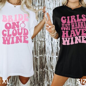 Peut inclure: Deux t-shirts surdimensionn&eacute;s avec un design de police r&eacute;tro. Le t-shirt blanc dit "Bride on Cloud Wine" avec un graphique de bague de fian&ccedil;ailles en diamant rose. Le t-shirt noir dit "Girls Just Wanna Have Wine". Les deux t-shirts sont de taille XL.