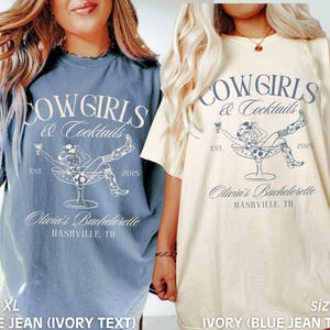 May include: Two oversized t-shirts featuring a cowgirl in a martini glass graphic and the text "Cowgirls & Cocktails" in blue. The left shirt is blue jean with ivory text. The right shirt is ivory with blue jean text. Both shirts say "Olivia's Bachelorette Nashville, TN" and "Est. 2025".