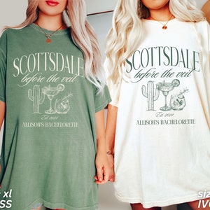 May include: Two oversized t-shirts, one moss green and one ivory, featuring the text "SCOTTSDALE before the veil" with a cactus and cocktail graphic. The text "Allison's Bachelorette" and "Est. 2024" are also printed on the shirts.