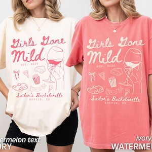 May include: Two oversized t-shirts with the text "Girls Gone Mild Est. 2025" and a graphic of a glass of wine, popcorn, pizza, and flip flops. The shirt on the left is ivory with watermelon text and the shirt on the right is watermelon with ivory text.