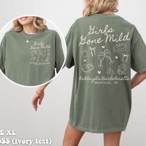 May include: Green t-shirt with the text "Girls Gone Mild" and a design of glasses, a sleep mask, and other hen party items. The text "Oakleigh's Bachelorette Knoxville, TN" is also on the shirt.