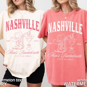 May include: Two oversized t-shirts, one ivory and one coral, feature a Nashville-themed graphic. The design includes the word "NASHVILLE" above a cowboy hat, boots, and a cocktail glass, with "Aria's Bachelorette" and "LET'S GO GIRLS" below.