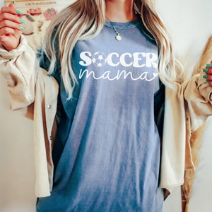 May include: A blue jean oversized t-shirt with the text "soccer mama" in white with a soccer ball graphic. The shirt is size XL.