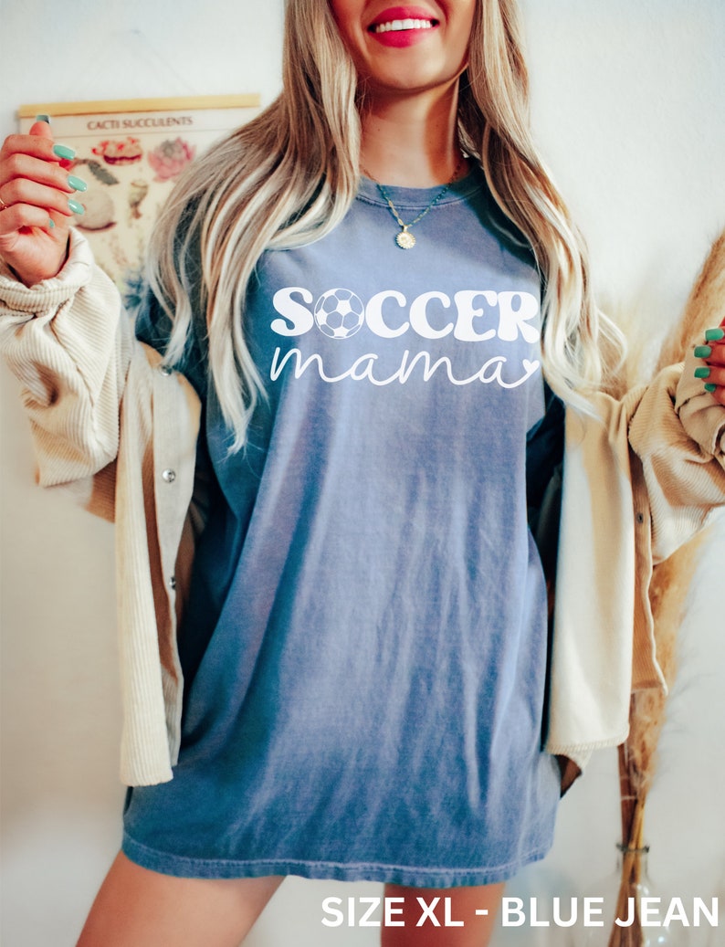 May include: A blue jean oversized t-shirt with the text "soccer mama" in white with a soccer ball graphic. The shirt is size XL.