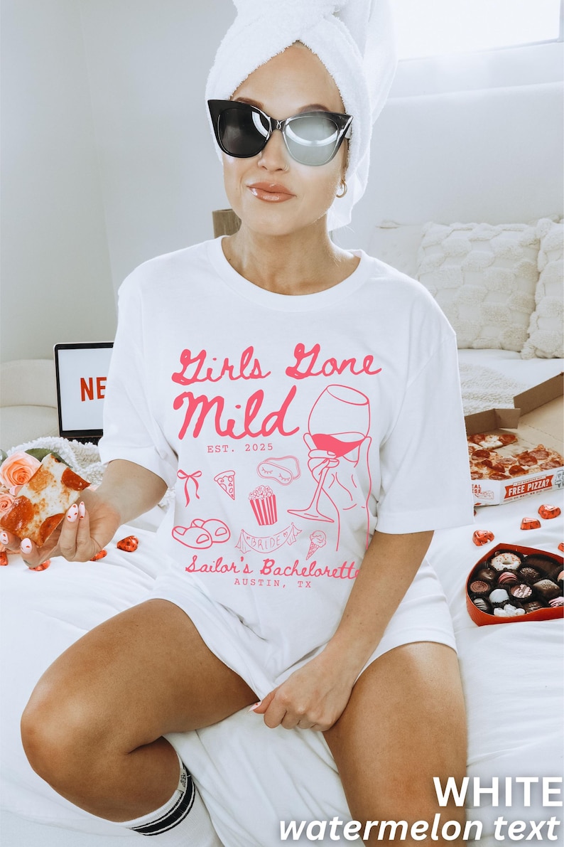 May include: White t-shirt with pink text that reads "Girls Gone Mild Est. 2025" and a graphic of a hand holding a glass of wine. The shirt also has a graphic of a pizza slice, popcorn, a sleep mask, flip flops, an ice cream cone, and the text "Sailor's Bachelorette Austin, TX".