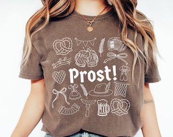 Puede incluir: Camiseta color espresso con un diseño gráfico blanco que presenta pretzels, jarras de cerveza y la palabra "Prost!" en negrita. La camiseta tiene cuello redondo y mangas cortas. Talla pequeña.