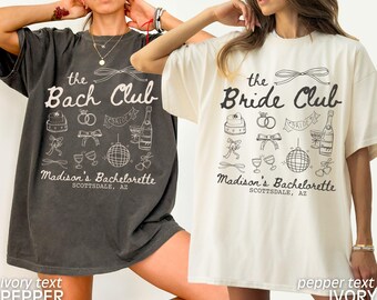 May include: Two oversized t-shirts with a bachelorette party theme. The left shirt is dark grey with ivory text that reads "the Bach Club" and the right shirt is ivory with pepper text that reads "the Bride Club". Both shirts feature a variety of wedding-themed illustrations and the text "Madison's Bachelorette Scottsdale, AZ".