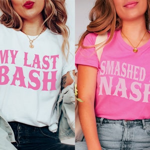 K&ouml;nnte beinhalten: Zwei T-Shirts, eines wei&szlig; und eines rosa, mit rosa Text. Das wei&szlig;e Shirt tr&auml;gt die Aufschrift "MY LAST BASH" und das rosa Shirt "SMASHED IN NASH". Beide sind kurz&auml;rmlig und haben einen l&auml;ssigen Stil.