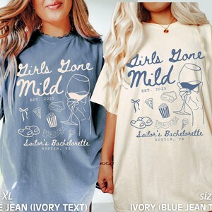 May include: Two oversized t-shirts with the text "Girls Gone Mild" and a wine glass graphic. The text "EST. 2025" and "Sailor's Bachelorette Austin, TX" are also included. One shirt is blue jean with ivory text and the other is ivory with blue jean text.