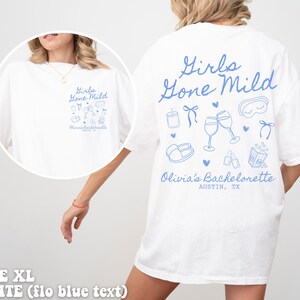 May include: White t-shirt with blue text that says "Girls Gone Mild" and includes illustrations of wine glasses, a sleep mask, and other party favours. The text "Olivia's Bachelorette Austin, TX" is also included.
