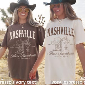 May include: Two t-shirts, one espresso and one ivory, with the word "NASHVILLE" arched across the top. Below, a cowboy hat, boots, and a cocktail glass are printed. The text "Aria's Bachelorette" and "LET'S GO GIRLS" are also visible.