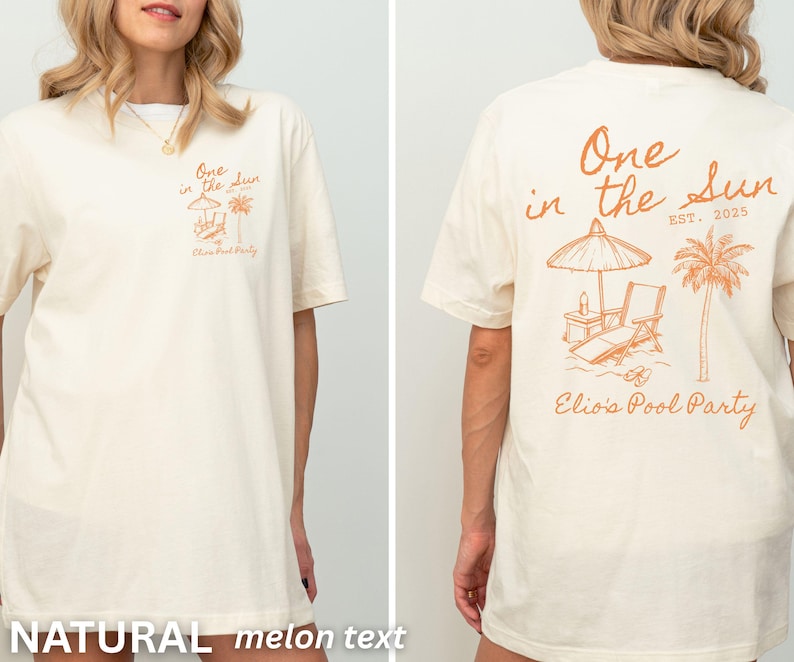 Op de afbeelding: Cr&egrave;mekleurig T-shirt met een oranje strandthema. De voorkant heeft tekst en een kleine illustratie, de achterkant een groter ontwerp met een parasol, stoel en palmboom. Tekst luidt "One in the Sun" en "Elio's Pool Party".