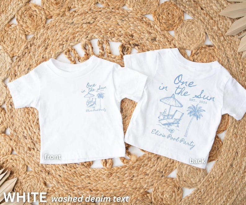 Op de afbeelding: Twee witte T-shirts met korte mouwen, met een blauwe afbeelding op de voor- en achterkant. Het ontwerp bevat de tekst "One in the Sun" met een strandsc&egrave;ne en "Elisa's Pool Party". De shirts worden gepresenteerd op een geweven mat.