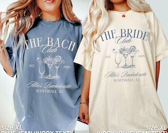 Puede incluir: Dos camisetas con un tema de despedida de soltera. La camiseta de mezclilla azul tiene el texto "The Bach Club" con un gráfico de margarita y el texto "Allie's Bachelorette Scottsdale, AZ". La camiseta de marfil tiene el texto "The Bride Club" con un gráfico de margarita y el texto "Allie's Bachelorette Scottsdale, AZ".