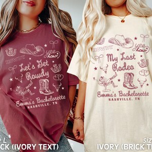 May include: Two t-shirts with a bachelorette party theme. The left shirt is brick red with ivory text that says "Howdy, Yee Haw, Let's Get Rowdy, Emma's Bachelorette, Nashville, TN". The right shirt is ivory with brick red text that says "Howdy, Yee Haw, My Last Rodeo, Emma's Bachelorette, Nashville, TN".