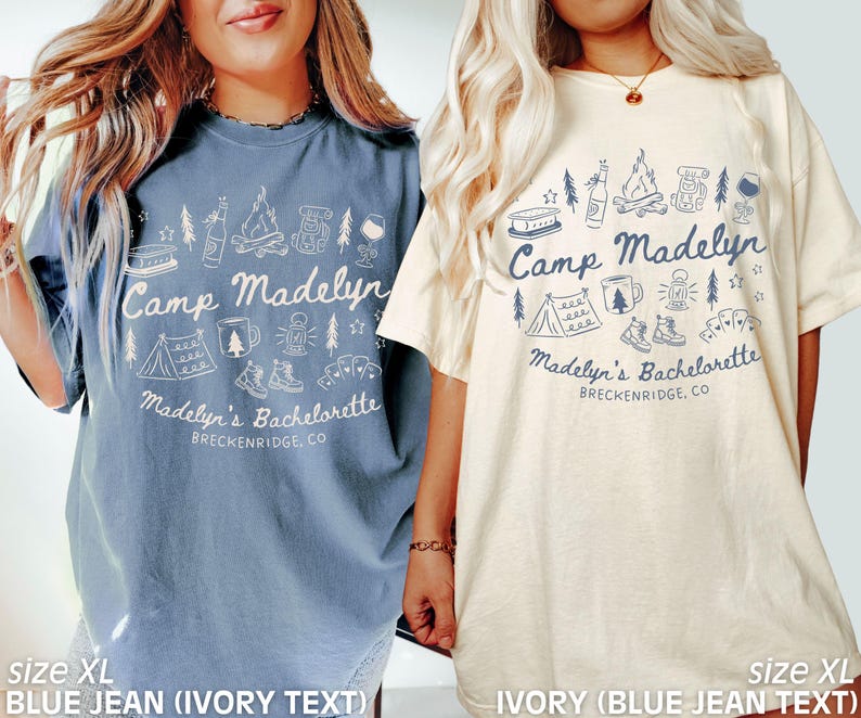 May include: Two XL t-shirts, one blue jean with ivory text and one ivory with blue jean text, both featuring a camping-themed graphic. The design includes a tent, campfire, and text that reads "Camp Madelyn" and "Madelyn's Bachelorette, Breckenridge, CO."