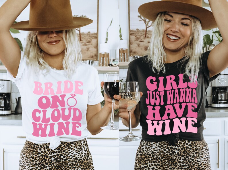 Peut inclure: Deux femmes portant des t-shirts avec du texte rose. La femme de gauche porte un t-shirt blanc avec le texte "Bride on Cloud Wine". La femme de droite porte un t-shirt noir avec le texte "Girls Just Wanna Have Wine".