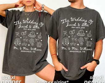 May include: Two charcoal gray t-shirts with a white graphic design. The graphic design features a wedding theme with the text "The Wedding of Jacob & Allie" and the date "May 18th, 2025". The shirts also include the text "Mr. & Mrs. Williams" and "Nashville, TN".