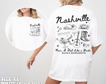 Può includere: Maglietta bianca con testo nero che dice "Nashville" e "Man, I Feel Like a Bride, Olivia's Bachelorette". La maglietta presenta una varietà di illustrazioni in bianco e nero tra cui un cappello da cowboy, stivali, una chitarra e una nota musicale.