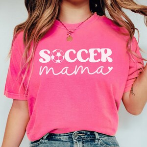 May include: A pink t-shirt with the text "SOCCER mama" in white with a white soccer ball graphic.