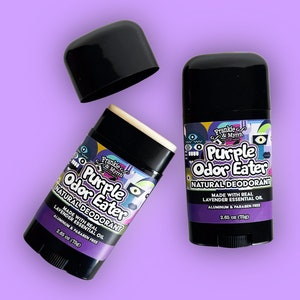 Op de afbeelding: Twee paarse en zwarte deodorant sticks met de tekst "Frankie & Myrrh Purple Odor Eater Natural Deodorant Made with Real Lavender Essential Oil Aluminium & Paraben Free 2.65 oz (75g)"