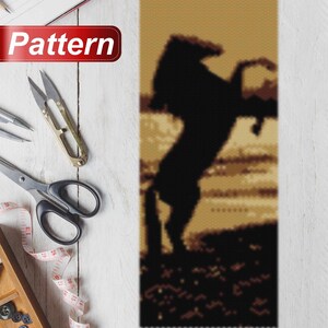 May include: A black and white pixel art pattern of a horse rearing up on its hind legs. The horse is silhouetted against a brown and beige background.