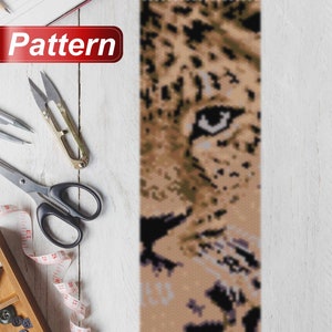 Op de afbeelding: Een close-up van een kralenpatroon van een luipaardgezicht. Het patroon is gemaakt met kleine, kleurrijke kralen en is een geweldig voorbeeld van kralenkunst.