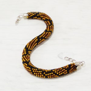 May include: A black and gold beaded bracelet with a silver clasp.