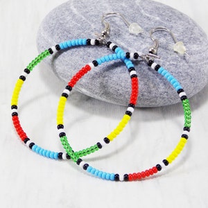 May include: A pair of colorful beaded hoop earrings with a black, white, red, yellow, and green color scheme. The earrings are made with small beads and have a silver hook closure.