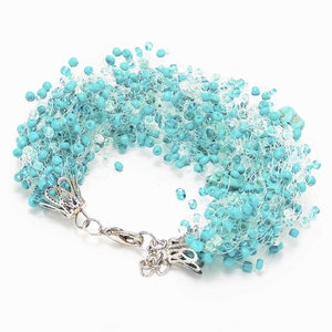 May include: A turquoise beaded bracelet with a silver clasp. The beads are strung on a white thread and create a fluffy, layered effect.