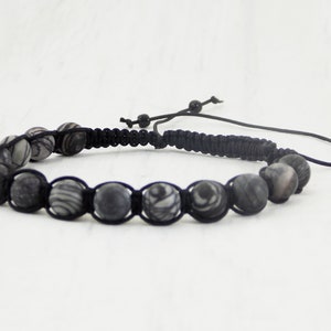 Puede incluir: Un brazalete trenzado negro con cuentas de patrones grises y blancos.