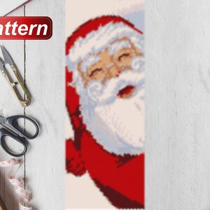May include: A close-up of a Santa Claus bead pattern for a Christmas craft project. The pattern features a red and white Santa Claus with a white beard and a red hat.