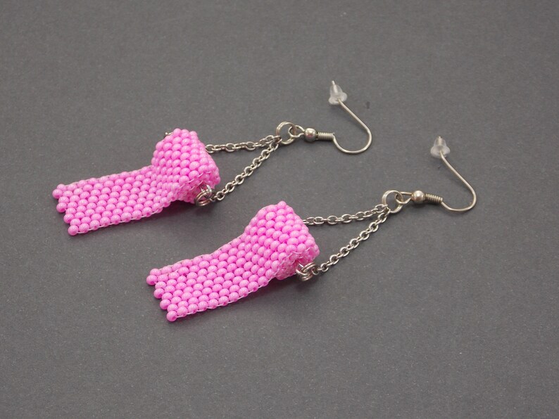 May include: A pair of pink beaded earrings with a rolled design and silver chains. The earrings have silver hooks.