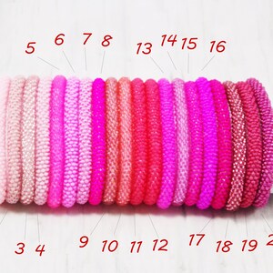 May include: Twenty pink and red beaded bracelets in various shades, numbered 1 through 20.