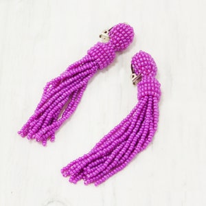 May include: A pair of purple beaded tassel earrings with silver clip-on closures.