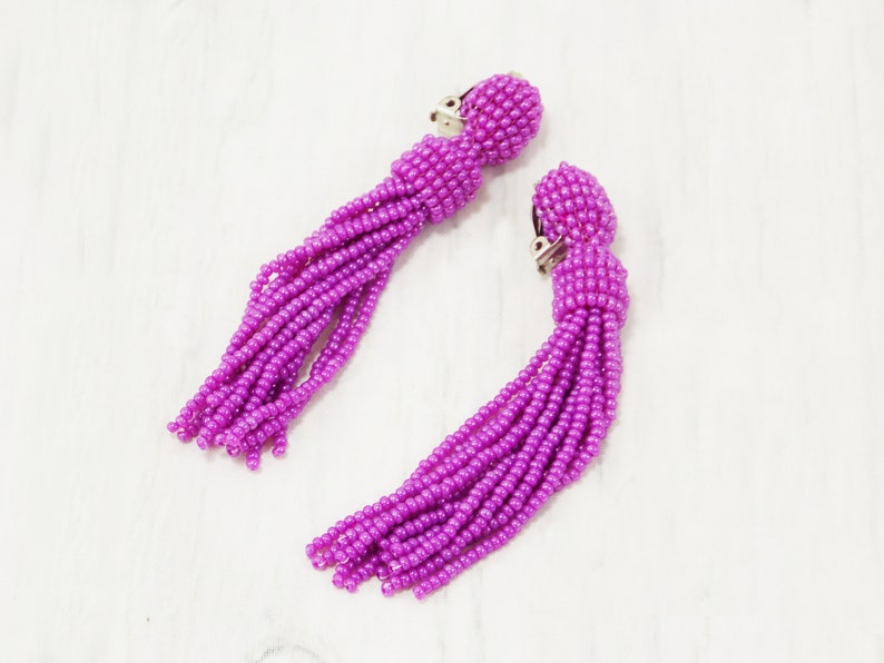May include: A pair of purple beaded tassel earrings with silver clip-on closures.