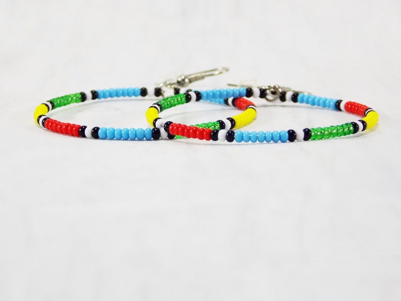 May include: Two colorful beaded bracelets with alternating colors of red, yellow, green, blue, white, and black.